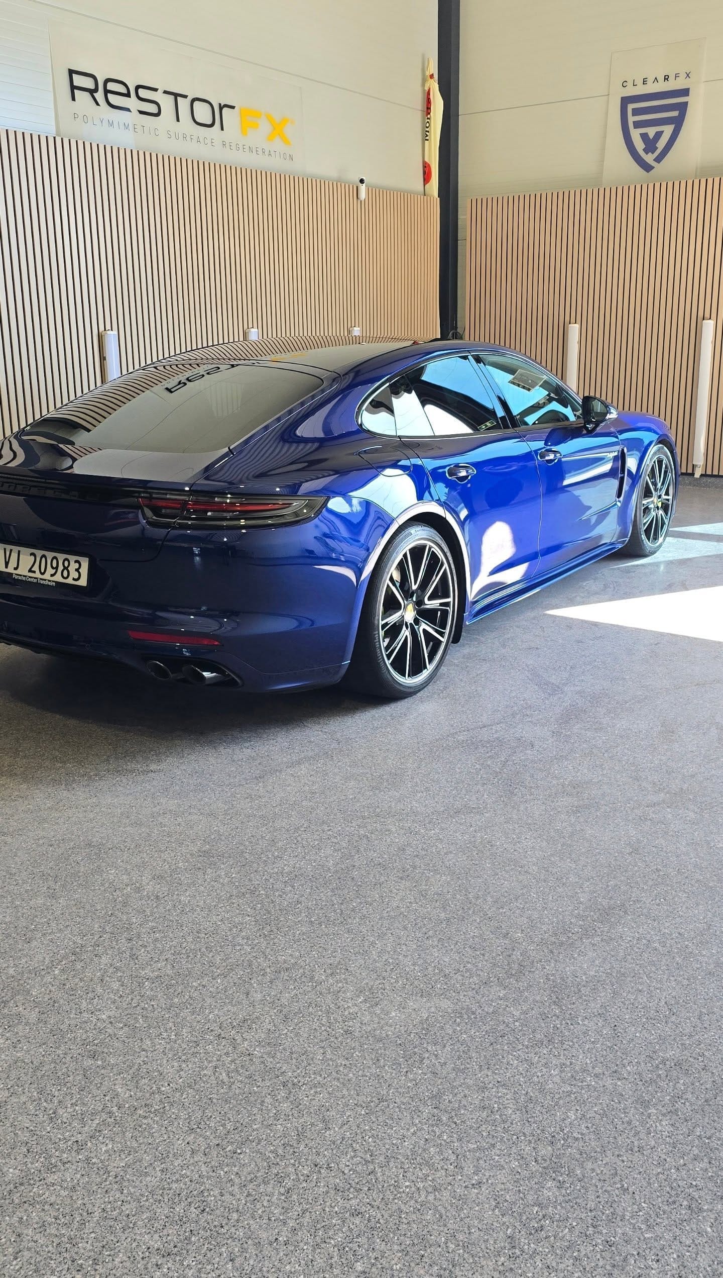 Mørkeblå Porsche Panamera med coatet lakk foran RestorFX-veggen i studioet