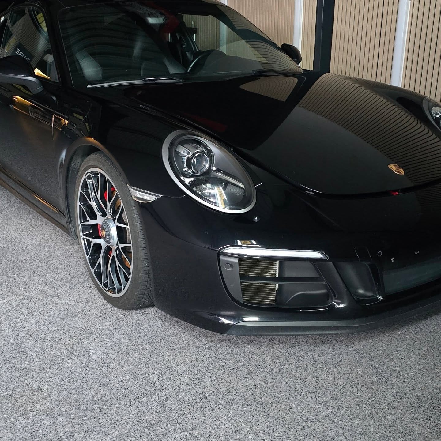 Svart Porsche 911 GTS med speilblank front i studioet
